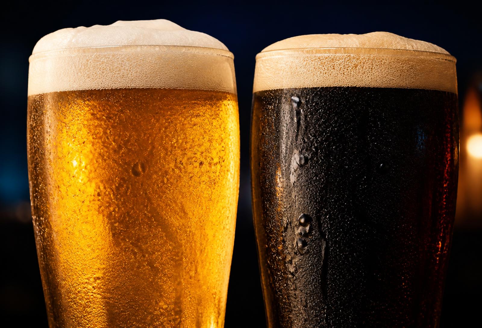 Dois copos de chopp gelado, um claro e um escuro, com colarinho espesso