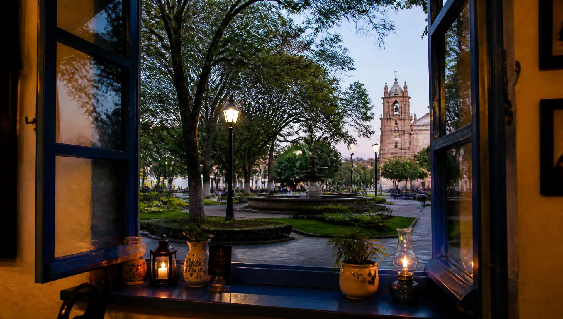 Vista da Praça Pedro Sanches através de uma janela de esquadria azul do Casarão